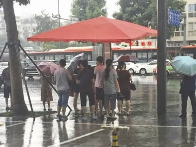 下雨天公交车站避雨1：市民纷纷聚集，分享各自的避雨小技巧与温暖故事，展现人间真情